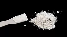 Alt text: Pile of White Chemical Powder on black table 