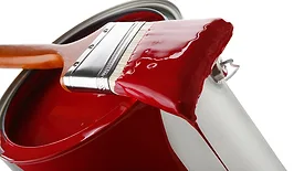 Thick red paint on brush sitting on paint can