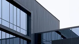 Modern commercial building facade with glass panels and dark metal cladding.