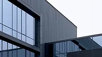 GI-2282029403-1170x658.jpg Modern commercial building facade with glass panels and dark metal cladding.