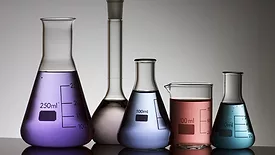 five laboratory flasks on a white backlight