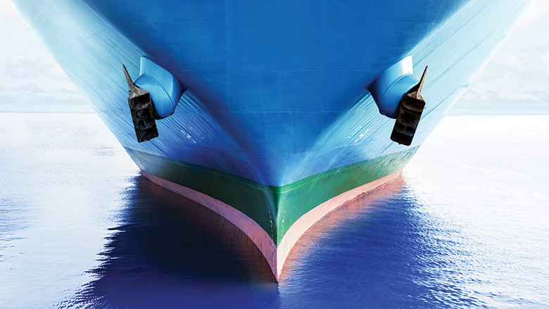 Front view of large blue merchant cargo ship with clean hull in the middle of the ocean