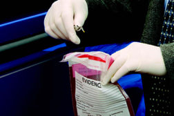 man placing object into evidence bag
