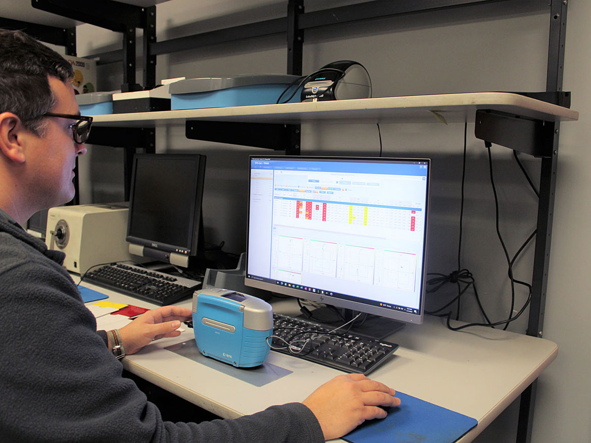 AkzoNobel’s Neil Szuma measures a painted panel with a spectrophotometer.