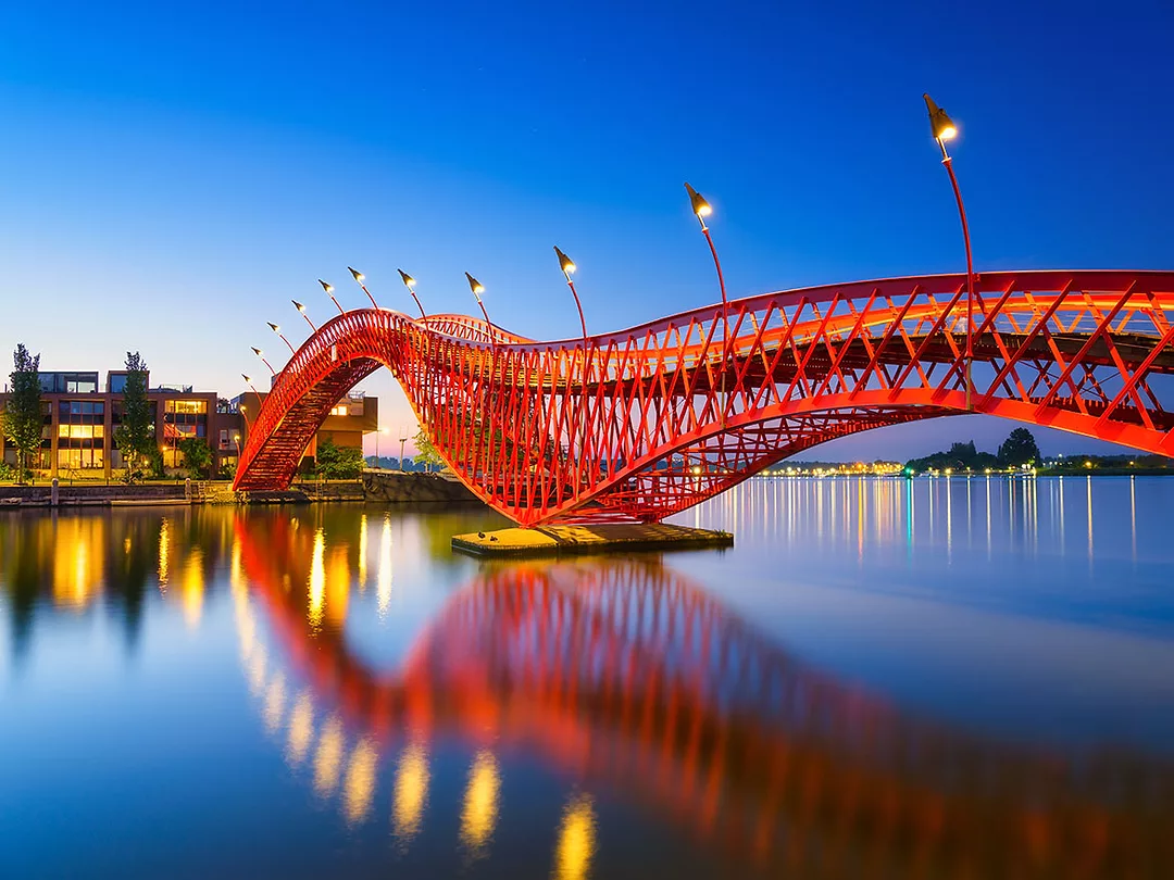 A bridge in the city at night. The bridge on the blue sky background during the blue hour. Architecture and design. The Python Bridge, Amsterdam, the Netherlands.