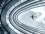 Low view blue colorized picture of modern architecture building with landing airplane in background