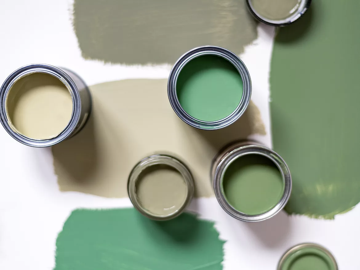 Tiny sample paint cans during house renovation, process of choosing paint for the walls, different green colors, color charts on background