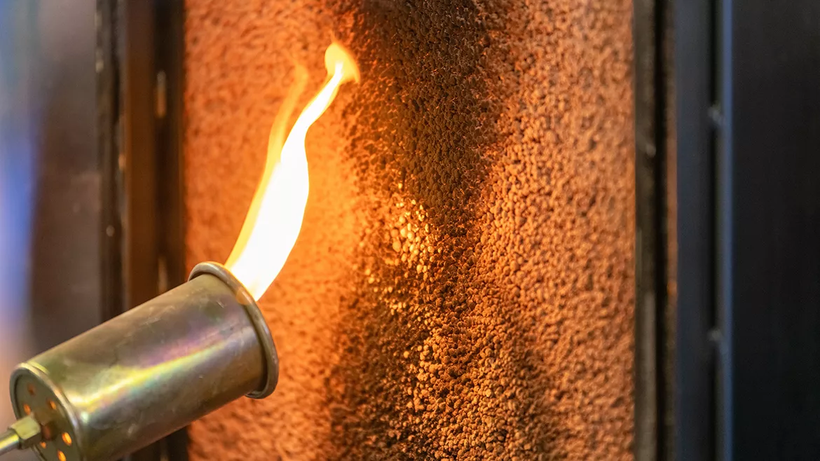 Close up of a flame torch testing flame retardant material, demonstrating fire resistance and safety in industrial applications