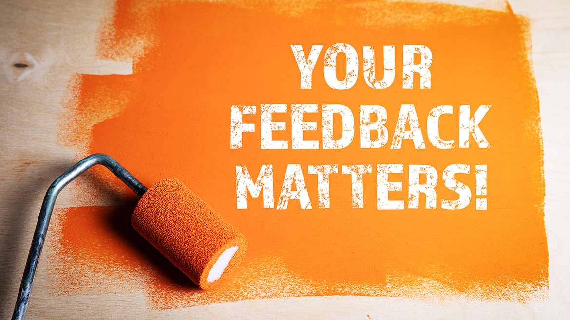 Orange painted wooden surface with paint roller and message in white: "Your Feedback Matters"