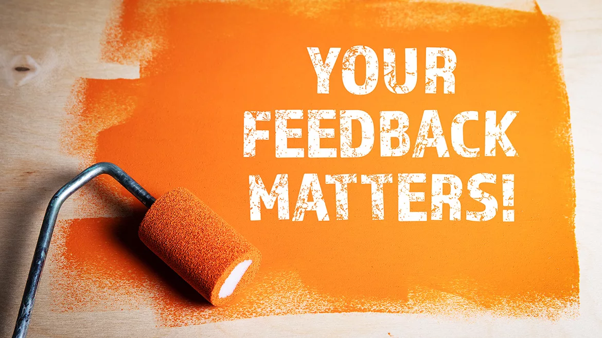 Orange painted wooden surface with paint roller and message in white: "Your Feedback Matters"