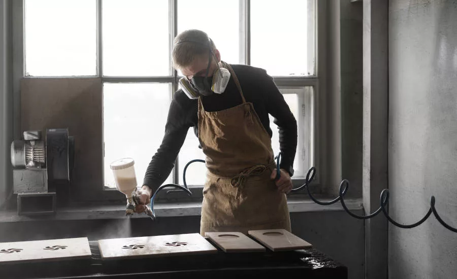 man painting gate in workshop