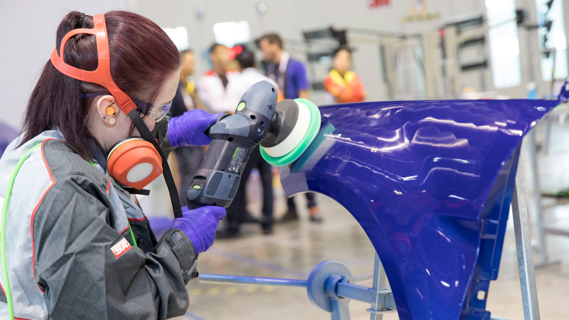 Photo of young woman buffing paint on an automotive part